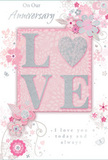 The anniversary card in this scene offers a gentle celebration of enduring romance, its design and colours echoing the soft elegance of an English spring garden arranged in a Finsbury studio. At its centre sits the word LOVE, formed from raised letters coated in soft, shimmering glitter. The letterforms appear smooth yet textured, as though a light dusting of frost has settled on them, catching and reflecting light with a quiet sparkle. The O takes on the suggestion of a heart, reinforcing the theme without overpowering the delicate style. Surrounding this focal point, an ensemble of blossoms in blush pink, mauve, and creamy white unfurls across a pastel pink backdrop. The petals are painted with an almost watercolour softness, their edges feathered and slightly translucent, like blooms illuminated by soft daylight over Finsbury's tree-lined streets. Fine, flowing lines sketch out stems, tendrils, and slender leaves that wind gracefully around the card, creating a sense of movement and care. Tiny decorative flourishes-curved swirls, small scattered petals, and subtle butterfly shapes-introduce a hint of playfulness, reminiscent of a garden stirred by a light breeze. The background maintains a gentle, consistent pink hue that feels comforting, neither too bright nor too muted, allowing the silver-grey accents to glint softly here and there. Elegant script reads On Our Anniversary and I love you today and always, the typography understated and warm, echoing the quiet sincerity of couples celebrating milestones in homes across Finsbury, Clerkenwell, and nearby Holloway. Overall, the card resembles a thoughtfully composed bouquet in printed form, ideal for accompanying a fresh anniversary floral delivery with its whisper-soft yet deeply heartfelt sentiment.